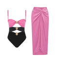 Load image into Gallery viewer, Pink and black luxury one-piece swimsuit with signature gold hardware and matching pink draped resort skirt