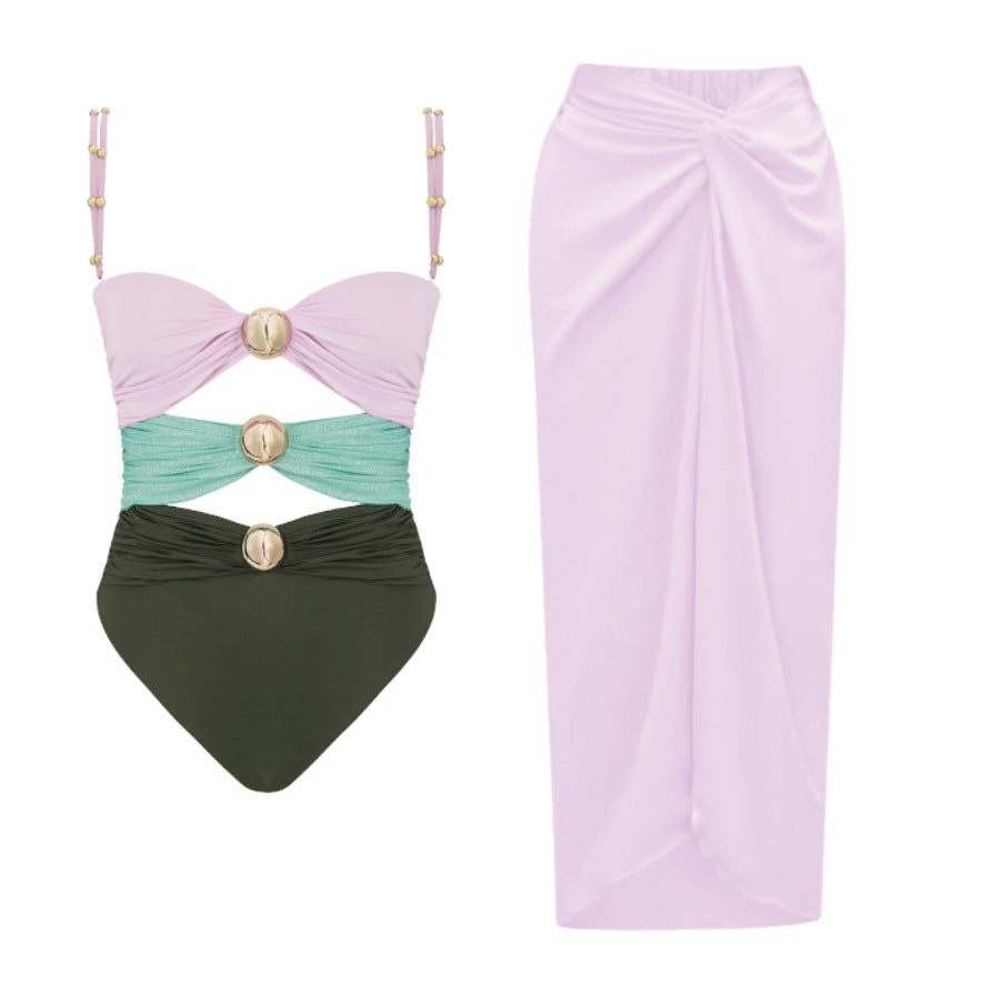 Pink and black luxury one-piece swimsuit with signature gold hardware and matching pink draped resort skirt